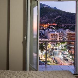 a bedroom with a window with a view of a city at Grand Olympic Hotel Loutraki in Loutraki