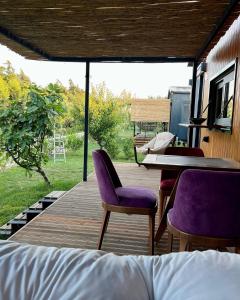 una terraza de madera con sillas moradas y una mesa en Tiny Datca en Datca