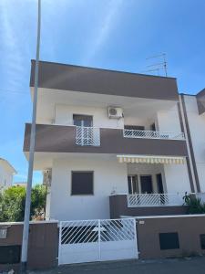 una casa blanca con una valla delante en Apartments happy family 1, en Marina di Ginosa