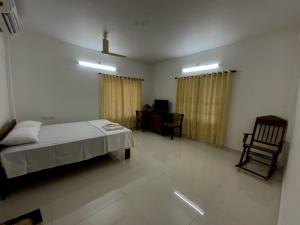 Un dormitorio con una cama, un escritorio y una silla. en PAZHOOR RESIDENCY HOME STAY 4BHK Deluxe, en Trivandrum