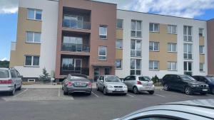 a parking lot with cars parked in front of a building at Saulužės guolis in Kretinga