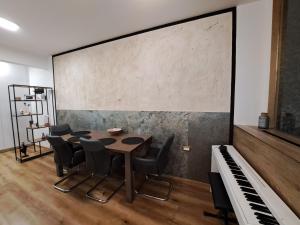 a room with a table and chairs and a piano at Stunning new apartment with free parking near city centre in Ljubljana