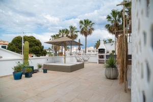 a patio with a couch and an umbrella on a roof at Casa Artrutx by GMHouse Menorca in Cala en Bosc