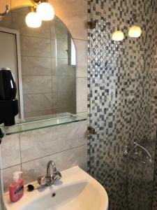 a bathroom with a sink and a shower with a mirror at AZALEA HOTEL in Sarti