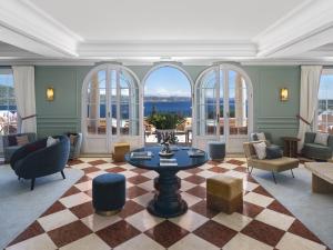 a living room with a table and chairs and windows at Althoff Hotel Villa Belrose in Saint-Tropez