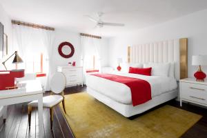 a white bedroom with a red and white bed and a desk at The Vendue, Downtown Art Hotel in Charleston