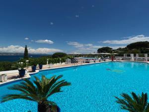 a large blue swimming pool with palm trees and chairs at Althoff Hotel Villa Belrose in Saint-Tropez