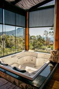 a bath tub in a room with large windows at Caminho das Nuvens - Cabanas de Montanha in Bom Retiro