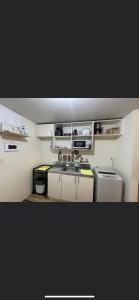 a small kitchen with white cabinets and a sink at Khentdrick's Place at Holland Park Southwoods in Biñan