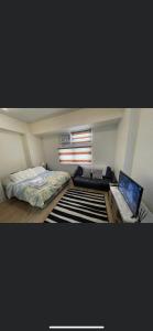 1 dormitorio con cama y escritorio con ordenador portátil en Khentdrick's Place at Holland Park Southwoods en Biñan