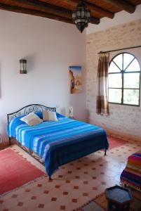 a bedroom with a bed with a blue comforter and a window at Riad Titima Essaouira in Essaouira