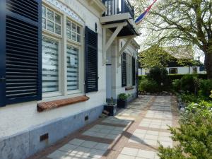 a house with blue shuttered windows and a sidewalk at De Waterlelie in Renesse