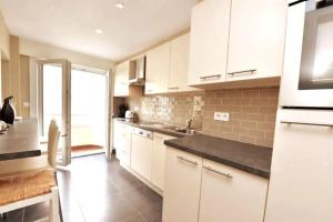 a kitchen with white cabinets and a black counter top at Knokke Top Bel Mooi appartement 8P Le Caducée in Knokke-Heist