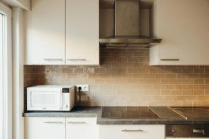 a kitchen with white cabinets and a microwave at Knokke Top Bel Mooi appartement 8P Le Caducée in Knokke-Heist +14 photos