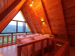 um quarto no sótão com uma cama e uma grande janela em Necran Bungalow اكواخ ايدر em Rize