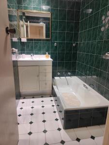 S&S Guest House في Armadale: حمام ذو بلاط أخضر مع حوض استحمام ومغسلة