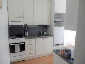 a kitchen with white cabinets and a stove and refrigerator at Kaksio Kemiönsaaressa in Björkboda