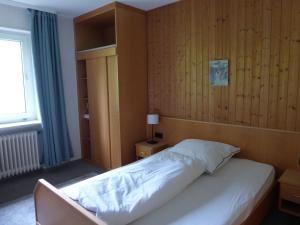 Schlafzimmer mit einem weißen Bett und Holzwänden in der Unterkunft Gasthaus Zum goldenen Löwen in Finkenbach