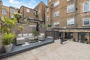 an outdoor deck with furniture in a building at Modern Garden Flat with Private Parking in London