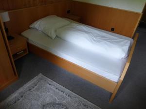 uma cama num pequeno quarto com lençóis brancos em Gasthaus Zum goldenen Löwen em Finkenbach