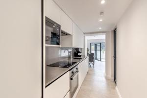 una cocina con armarios blancos y electrodomésticos de acero inoxidable en Modern Garden Flat with Private Parking, en Londres