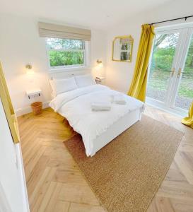 a bedroom with a white bed and a large window at Orchard Cottage - Kent in Lyminge