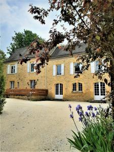 a large brick building with white windows and purple flowers at Manoir Petit Meysset in Sarlat-la-Canéda
