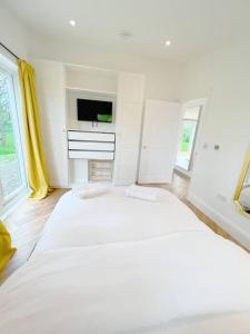 a white bedroom with a large bed and a tv at Orchard Cottage - Kent in Lyminge
