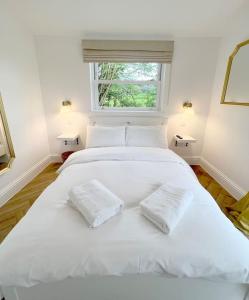 a bedroom with a large white bed with two pillows at Orchard Cottage - Kent in Lyminge
