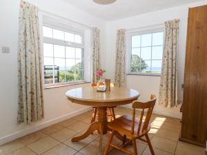 Un comedor con una mesa y dos ventanas. en Min Y Mor, en Criccieth