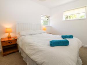 een slaapkamer met een wit bed met blauwe kussens erop bij Min Y Mor in Criccieth