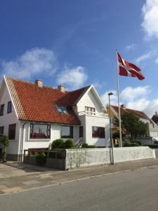 a white house with a flag in front of it at Penthouse Apartment Downtown - Hotel Sønderstrand Apartments in Skagen