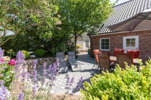 a patio with a table and chairs and flowers at Haus zu den Halligen in Bredstedt