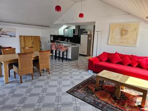 a living room with a red couch and a kitchen at Seeblick Kampf mit Fahrradgarage in Nonnenhorn