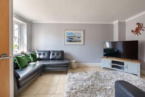a living room with a leather couch and a flat screen tv at 1 Afon y Felin in Abersoch