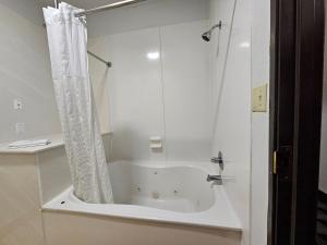a white bath tub with a shower curtain in a bathroom at Quality Inn & Suites Irving DFW Airport South in Irving