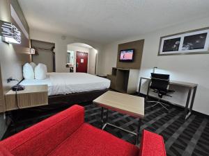 a hotel room with a bed and a red couch at Quality Inn & Suites Irving DFW Airport South in Irving