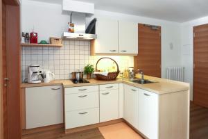 una cocina con armarios blancos y fregadero en Waldthalerhof, en Monticolo