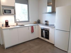 een keuken met witte kasten en een witte koelkast bij T3 contemporain, plein centre, terrasse et parking in Bayonne