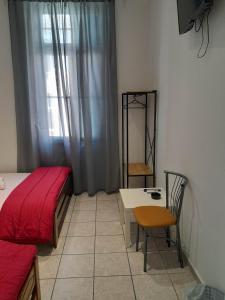 Schlafzimmer mit einem Bett, einem Tisch und einem Fenster in der Unterkunft Ikaros in Piräus