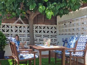 a woman sitting at a table under a tree at Riumar "Camins", 380m to beach, private pool, On-Site-Service, dog beach in Riumar