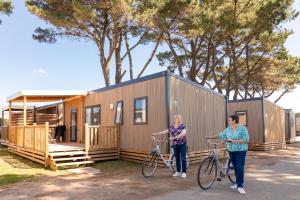 twee vrouwen staan met hun fiets voor een klein huisje bij Camping Park Er Lann in Saint-Pierre-Quiberon