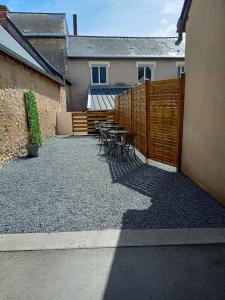 un patio con mesa, sillas y una valla en Appart 3 chambres, en Noyen-sur-Sarthe