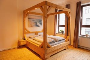 ein Holzbett in einem Zimmer mit 2 Fenstern in der Unterkunft Up'n Swutsch im Norden am Meer in Bremerhaven