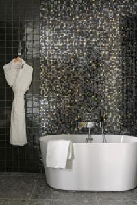 MiHotel Sala في ليون: حوض استحمام أبيض في حمام به جدار من البلاط