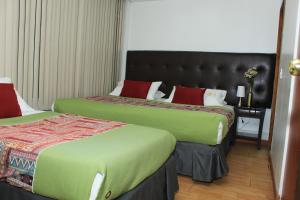two beds in a hotel room with green and red at Suna Bacata in Bogotá
