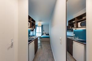 a kitchen with blue walls and wooden cabinets at Cute Studio close to Paris - 1P - 422 in Ivry-sur-Seine