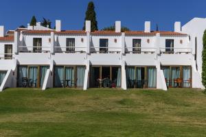 an exterior view of a large white building with tables at Pedras D'el Rei in Tavira