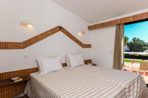 a bedroom with two beds and a large window at Pedras D'el Rei in Tavira
