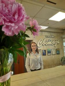 une femme debout à côté d'une table avec des fleurs roses dans l'établissement Svytyaz Hotel, à Loutsk